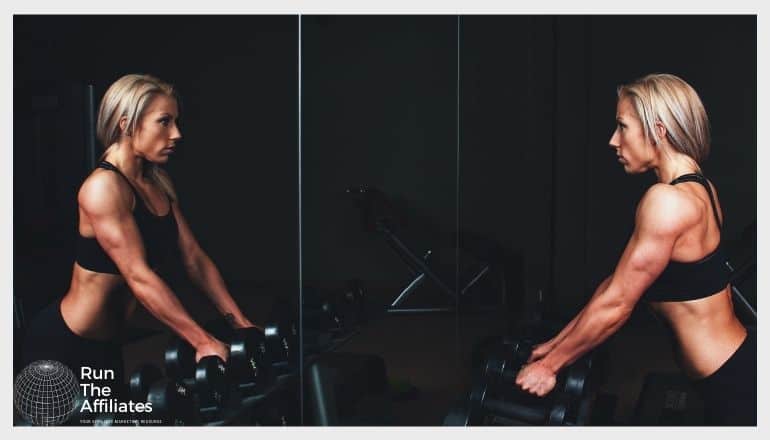 woman bodyvuilding looking in a mirror as she prepares to lift weights