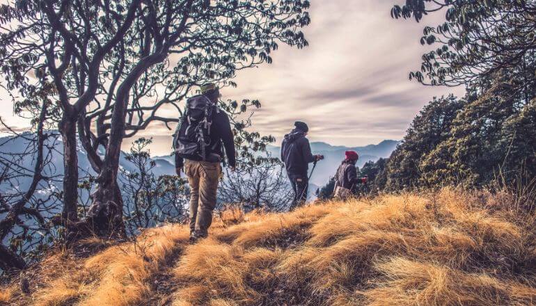 3 people hiking through field