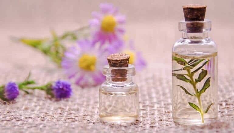 2 essential oils and a variety of flowers laying on a table