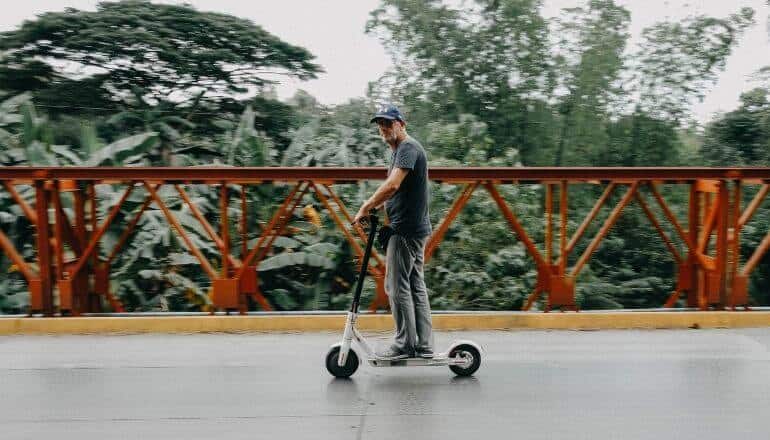 man on scooter in front of guard rail