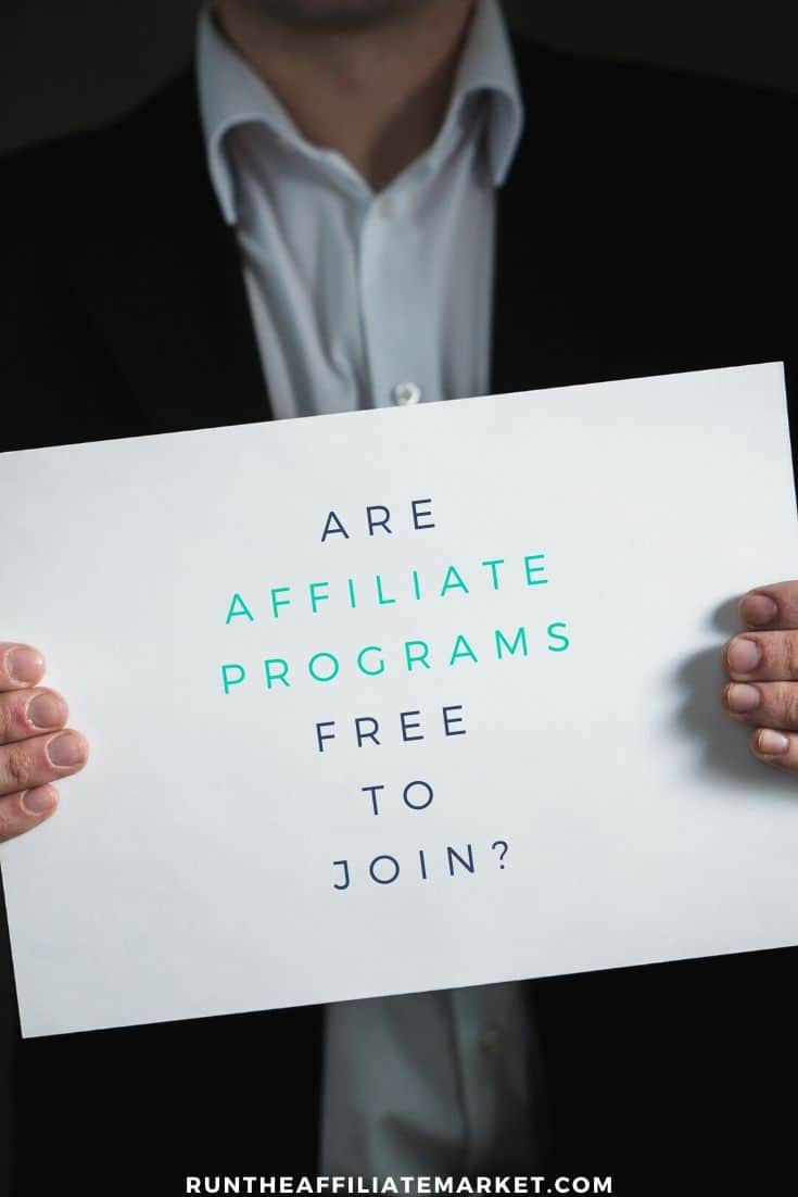 man in black suit and white shirt holding large white card with are affiliate programs free to join written on it.