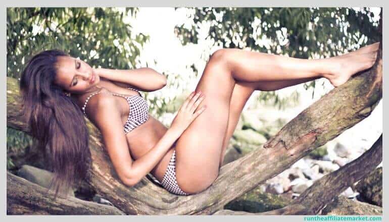 woman in checkerboard bikini lying on a tree branch