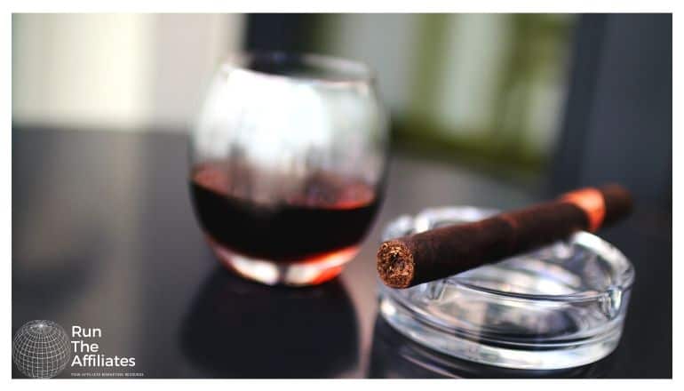 cigar resting on an ashtray next to a glass of brandy