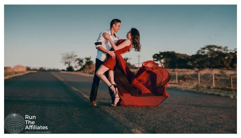 man and women in red dress dancing on a deserted road