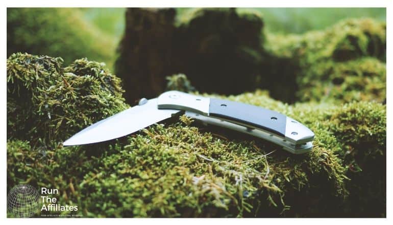 pocket knife resting on a moss covered rock in the forest