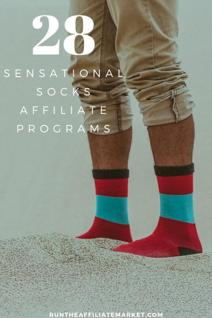 man wearing tan slacks and red and blue socks standing in sand