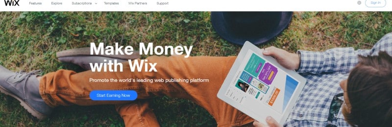 screenshot of the wix affiliate program webpage featuring a man sitting on the grass looking a a tablet.