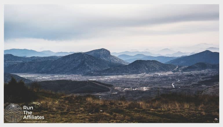 image of wilderness with a grey sky and mountains looming in the background