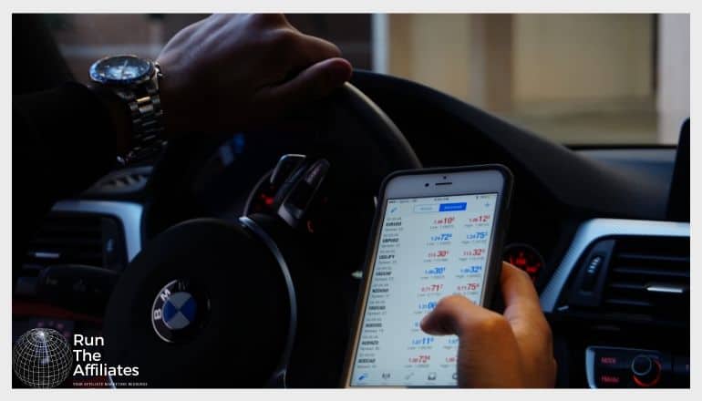 man looking at forex market on smartphone in a car