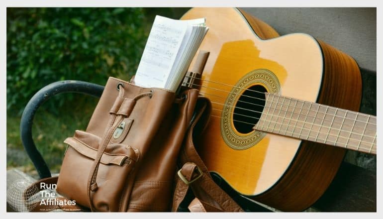 yellow acoustic guitar on a park bench next to a backpack