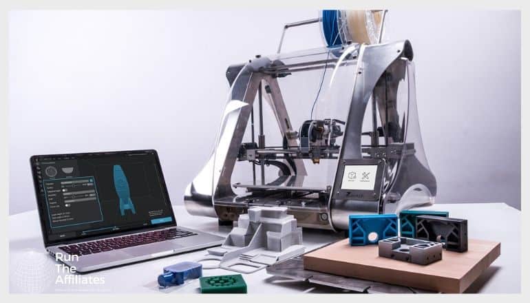 3d printer next to a laptop with a scematic of a blue rocket on the screen