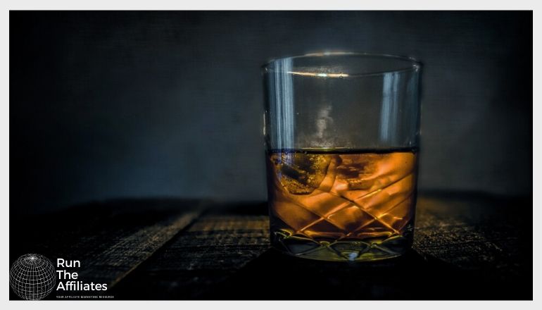 glass of whiskey with ice against a dark background