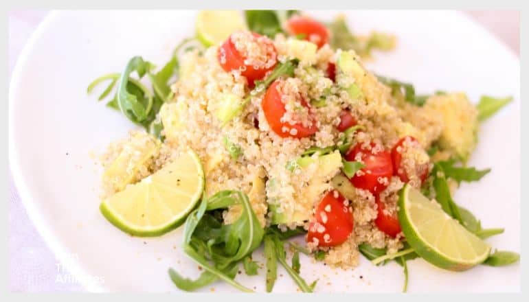 quinoa dish with tomatoes greens and limes served on a white plate
