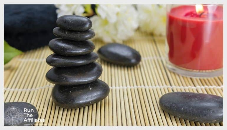 smooth black rocks stacked next to a red lit candle