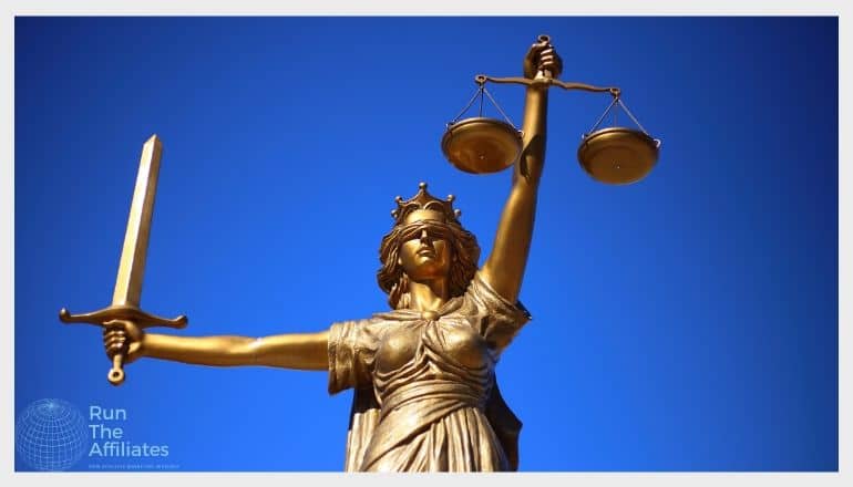 bronze lady justice holding a sword and scales against a deep blue sky background
