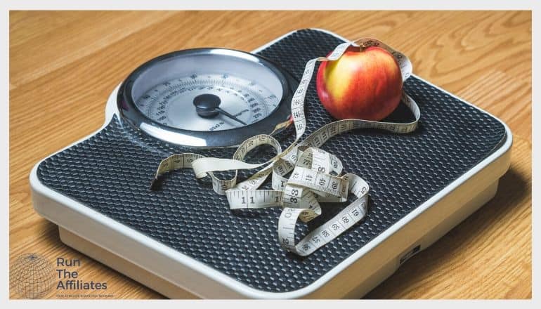 a red apple and a measing tape on a weight loss scale