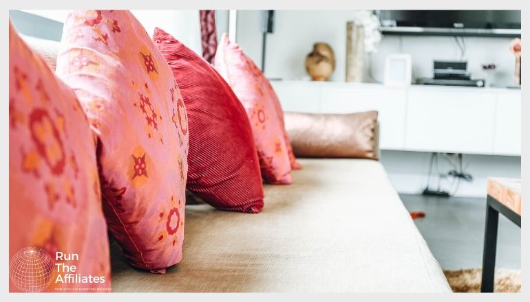 a row of pink and red throw pillows on an off-white sofa