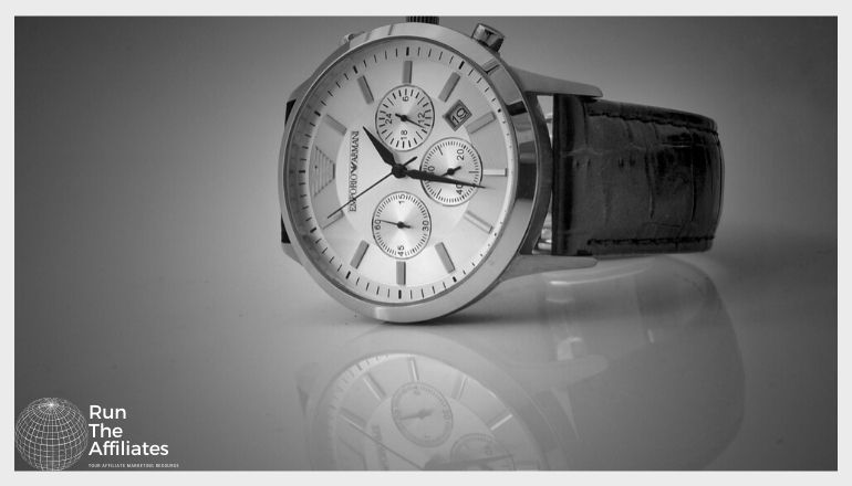 silver watch with dark band setting on a reflective surface