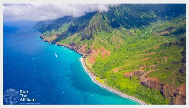 arial view of the Hawaii coast line with deep blue water and green hills and mountains