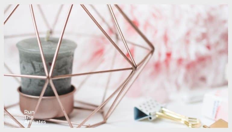 candle in a copper holder surrounded by a copper geometric shape