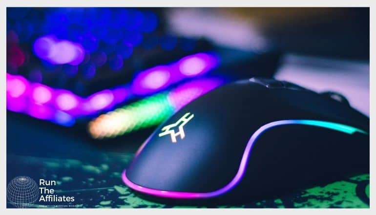 a close up of a computer mouse with purple and blue led lights with an out of focus keyboard in the background