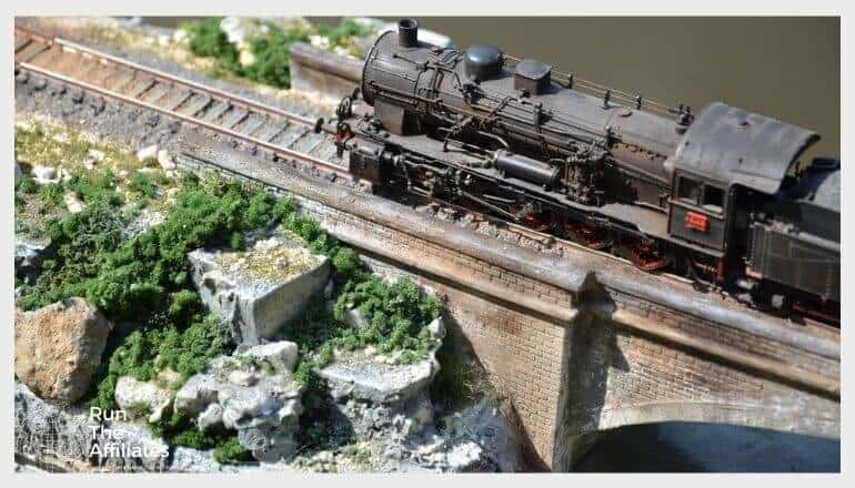 diorama of a model train crossing a bridge over water