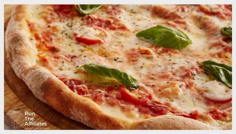 close up of a pizza with tomatoes and green basil leaves