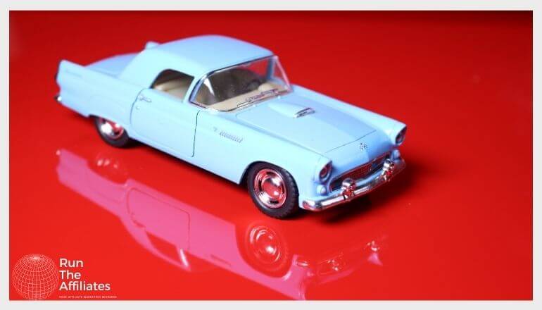 blue diecast car on a glossy red tabletop