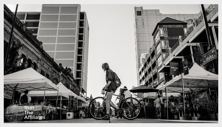 black and white photo of man on bike in the city